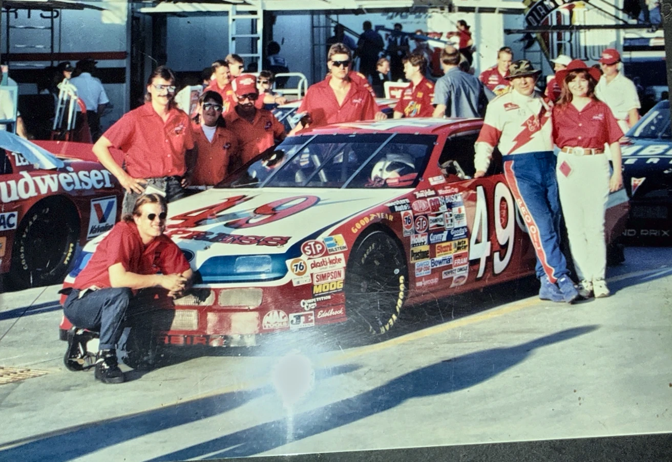 Historical photograph of the number 49 race team gathered around the race car