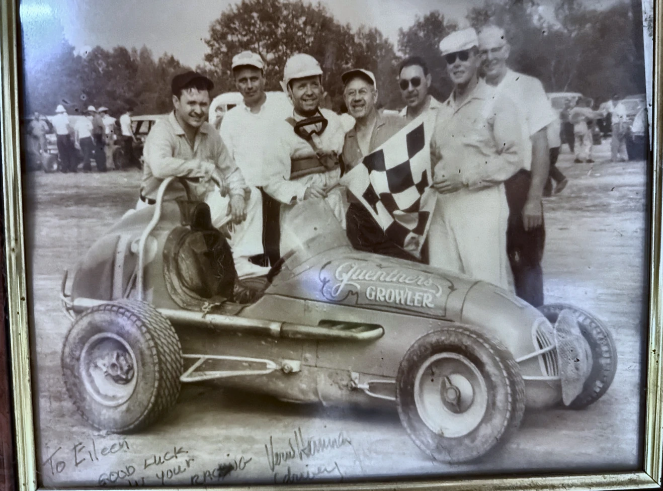 Vintage victory photograph with a checkered flag and open-wheel race car