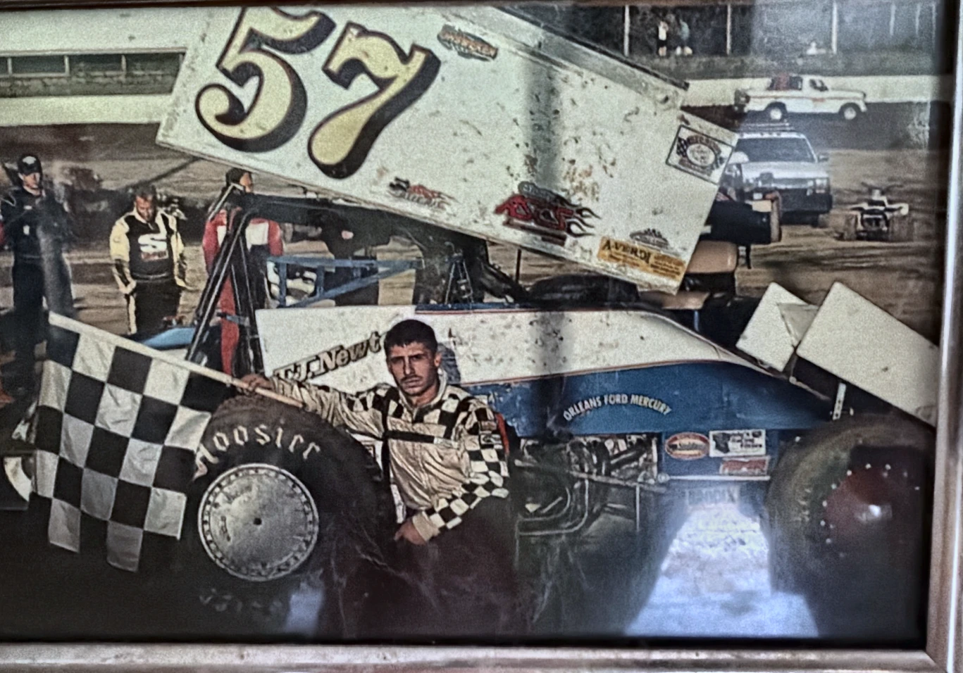 Historical photograph of the number 57 race car and driver with a checkered flag