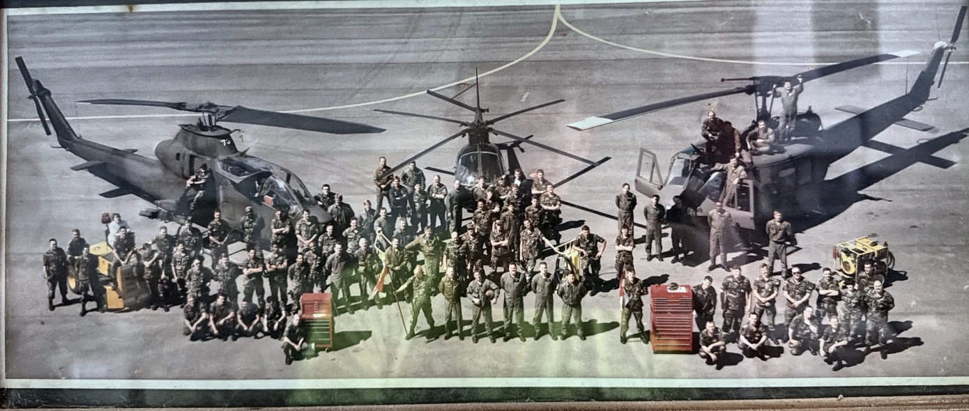 Historical group photograph with three helicopters on a flight line
